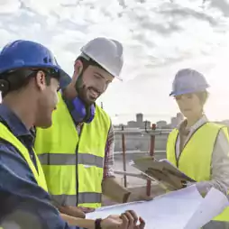 people - 3 people in yellow vests and hard hats reviewing plans